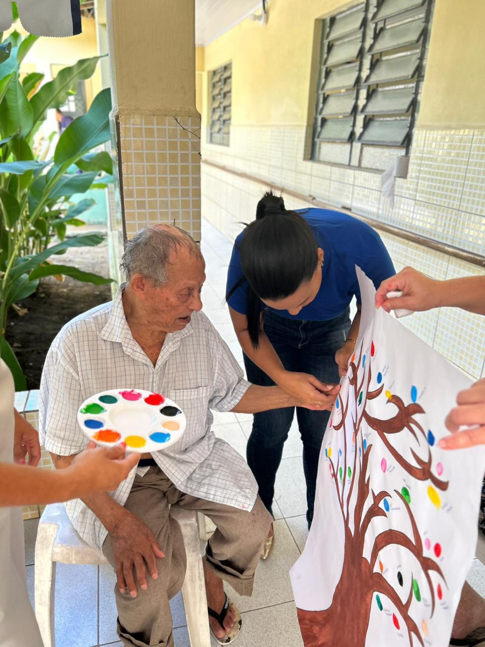 Residente participando de pintura coletiva em mural